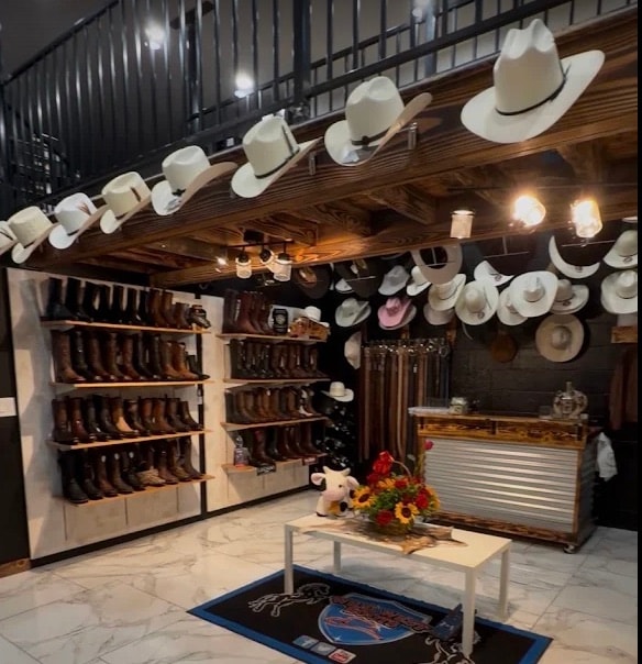 Inside the Santa Maria store: a wall of boots beside hats lining a timber beam, under the mezzanine rail